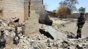 A Nigerian soldiers stands beside a burnt house after the army clashed with Boko Haram insurgents in Borno state. Photo: April 2013