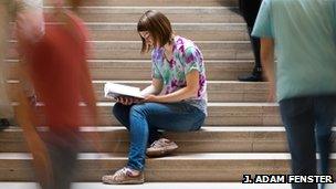 A woman focusing on reading a book while people rush around her