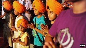 Indian Sikh members praying after a turban-tying ceremony known as 'dastar bandi', traditionally held to mark the coming of age of male Sikhs, at a temple in Amritsar 7 July 2012