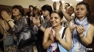 Relatives and friends of the accused cheer them as they arrive at court, 6 June