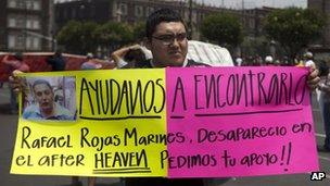 A man holds a placard asking for help with the search of a group of missing youngsters in Mexico City on 40 May 2013
