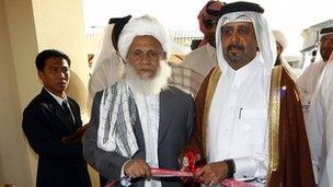 A Qatari official, center right, and Taliban official Jan Mohammad Madani, center left, cut the ribbon at the official opening ceremony of a Taliban office in Doha
