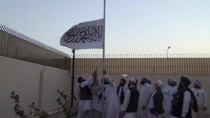 Taliban members raise the group's flag at the office in Doha