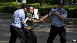 File photo: a petitioner trying to attract public attention is taken away by policemen in Beijing, China, 8 May 2012