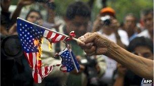 A woman burns US flags during a protest in support of Bolivian President Evo Morales in front of the US embassy in Mexico City, on 4 July