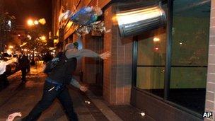 A man throws a trash can at the window of a building during a protest after George Zimmerman was found not guilty in the 2012 shooting death of teenager Trayvon Martin 14 July 2013
