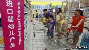 A family looks at foreign imported milk powder products at a supermarket in Beijing July 3, 2013.