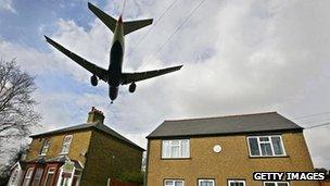 A passenger jet flies over rooftops as it prepares to land at Heathrow airport in west London