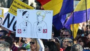 A protester in Madrid holds a poster comparing Angela Merkel to Adolf Hitler. Photo: June 2013