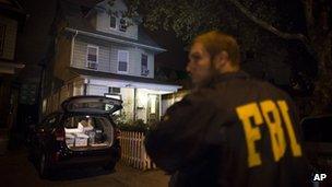 An FBI agent stands guard as evidence sits in the trunk of a vehicle at the Brooklyn residence of Rabbi Mendel Epstein during an investigation, 10 October 2013