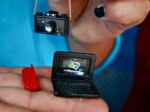 Woman holds miniatures of camera, laptop and mobile phone