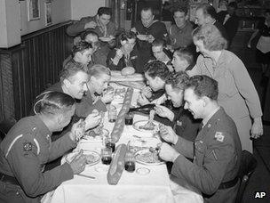 Anita O’Mera, of the staff of the Stage Door canteen, serves the wine to U.S. Army, Navy and Canadian Army men while Joe, the boss of Colucci’s hands around the spaghetti and pizzeria in New York on Dec. 26, 1942.