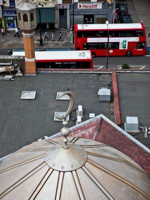 An aerial view of a mosque, with a road and two London buses in the background