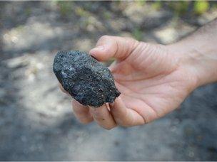 A miner holds out a piece of coal