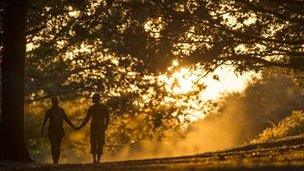 A couple walk through Richmond Park at sunset on September 12