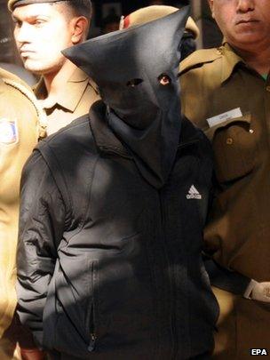 Police personnel escort taxi driver (wearing mask), accused of raping a female finance company executive, as he is taken to court in New Delhi, 08 December 2014.