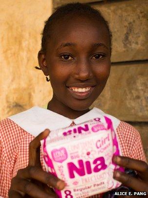 A Kenyan schoolgirl holding a pack of Zana Africa-made sanitary pads