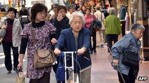 Elderly people walk down a busy street