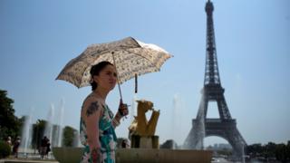 A woman cools down at the fountains of Trocadero, across from the Eiffel Tower, during a heatwave in Paris, France,