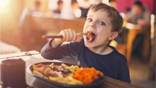 Niño comiendo carne.