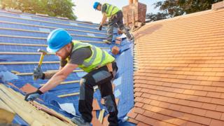 Workers tiling a roof