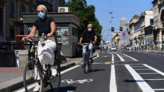 People ride their bicycle through a bike lane in central Milan on 4 May