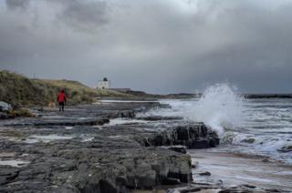 Waves crashing against rocks by a Lighthouse