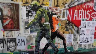 A uniformed man drags a protester by her neck