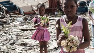 Aworan awọn ọmọbinrin to n ṣa ododo nibi awọn ile ti o wo ni ilu Beira lọjọ aiku.