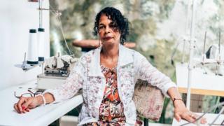 Mujer sentada junto a máquina de coser.