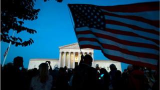 A person holds a US National flag outside of the US Supreme Court