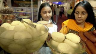 Две индийские женщины смотрят на разаголлы, выставленные в Калькутте