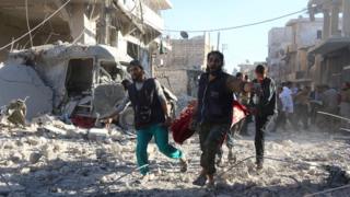 Syrian volunteers carry injured person on a stretcher following Syrian government air strikes on rebel held neighbourhood of Heluk in Aleppo, on September 30, 2016.