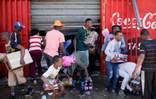 Looters take goods out of a store