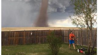 La foto de Theunis Wessels podando el césped con el tornado tras él