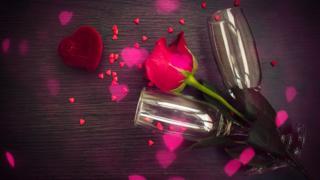 Unas copas de champaña con una rosa roja y unos corazones