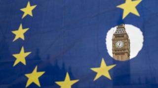El Big Ben de Londres visto a través de un agujero en la bandera de la Unión Europea.