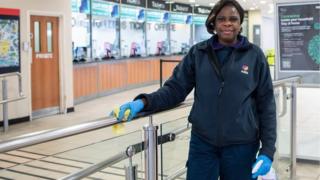 Frau reinigt Handlauf im Bahnhofskassenschalter