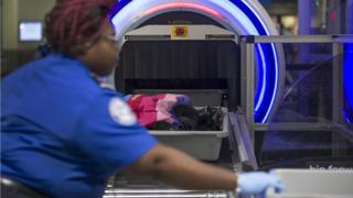 Hình ảnh tập tin của một nhân viên an ninh sân bay giúp du khách đặt túi qua máy quét 3D tại sân bay quốc tế Miami vào tháng 5 năm 2019