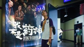   A girl walks past a poster of the movie Dying to Survive in a movie theater in Beijing, July 12 