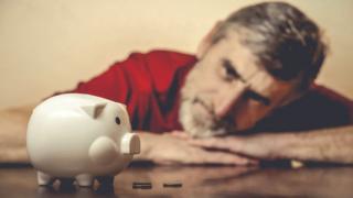 man looks at piggy bank