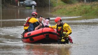 A family in a boat is helped by emergency workers in Nantgarw, Wales