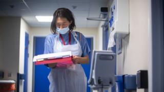 A doctor looks at a patient's notes at NHS Seacole Centre in Surrey