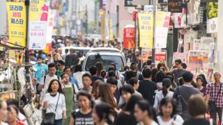 Gente caminando en calle comercial en Seúl, Corea del Sur.