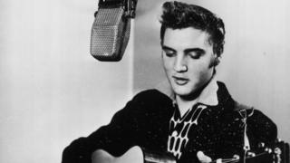 Elvis Presley retratado em uma cabine de gravação, tocando uma guitarra