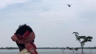 हेलीकॉप्टर देखते एक बाढ़ पीड़ित