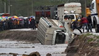 A man is assisted to climb off a truck that was washed off a road by flash floods at Isinya some 58kms south-east of Nairobi on March 15, 2018.