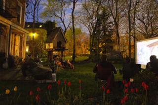 Maddie's family watches a movie outside with their neighbours