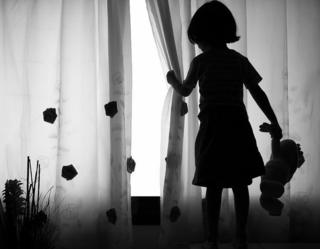 small girl wey dey look outside from window