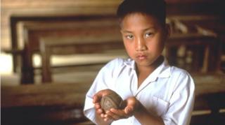 A young Laotian boy holds a model of a "bombie," or cluster munitions